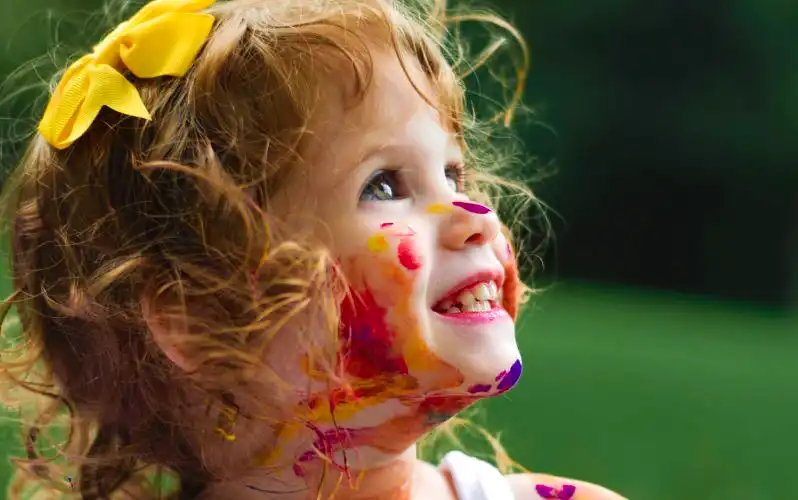 Mała dziewczynka z farbami na twarzy